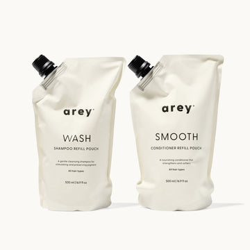 Two arey shampoo and conditioner refill pouches on a white background