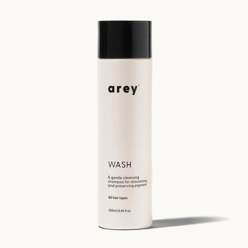 Arey Wash bottle on a cream background. Label reads: arey. WASH. A gentle cleansing shampoo for stimulating and preserving pigment. All hair types. 250ml / 8.45 fl oz.