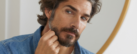 Handsome man looks at grey hair in his beard