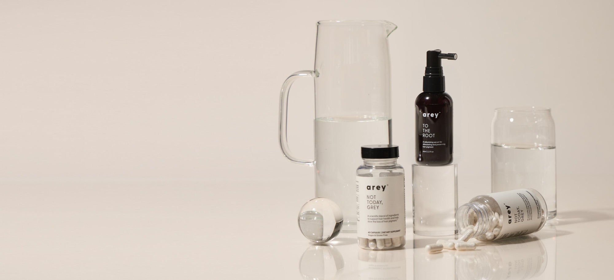 Collection of haircare products on a reflective surface with a neutral background