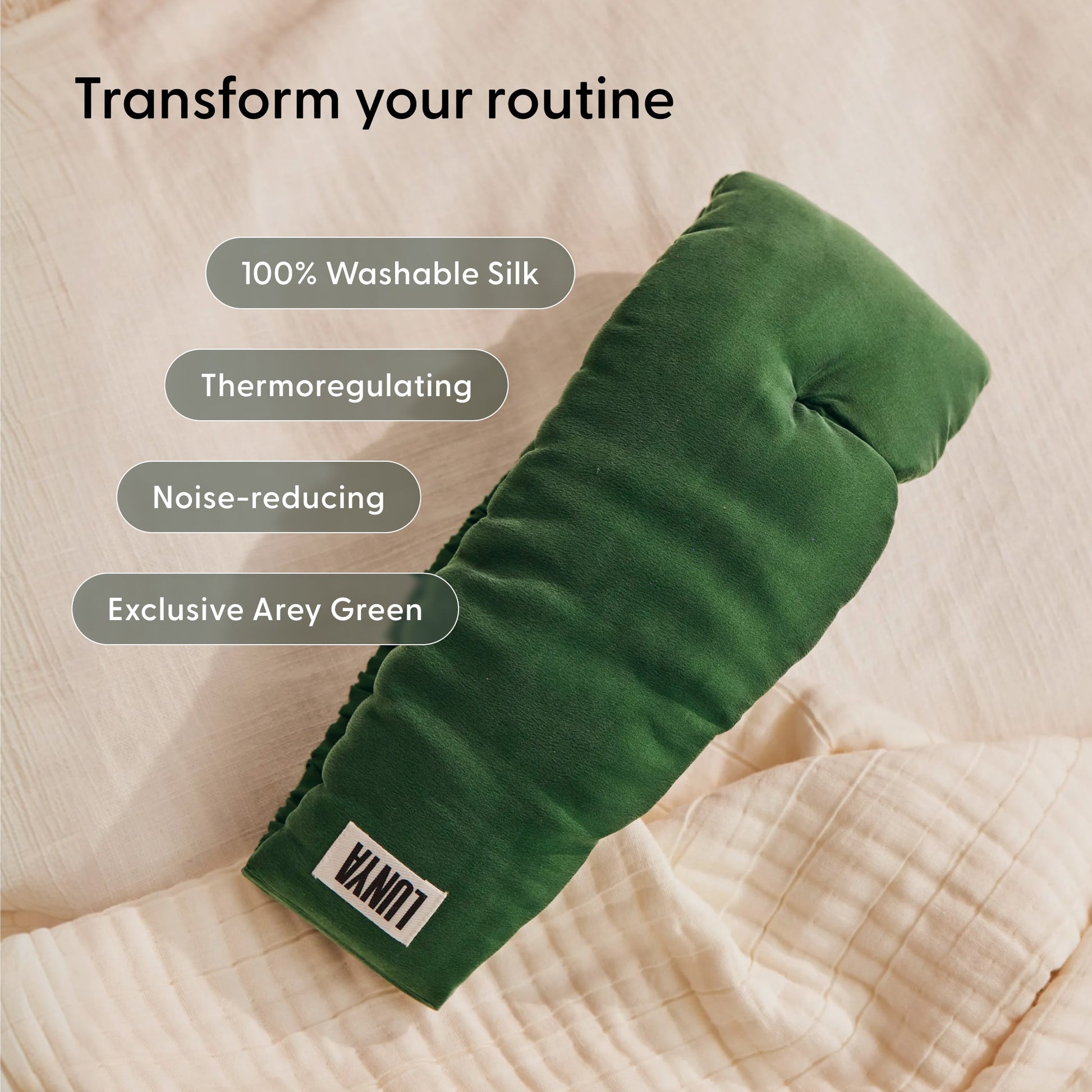 A padded sleep mask from Arey’s Beauty Sleep Duo in the exclusive Arey Green shade, labeled LUNI, rests on a beige quilt. Made from 100% washable silk, this thermoregulating and noise-reducing mask is designed to enhance your nightly hair wellness routine.