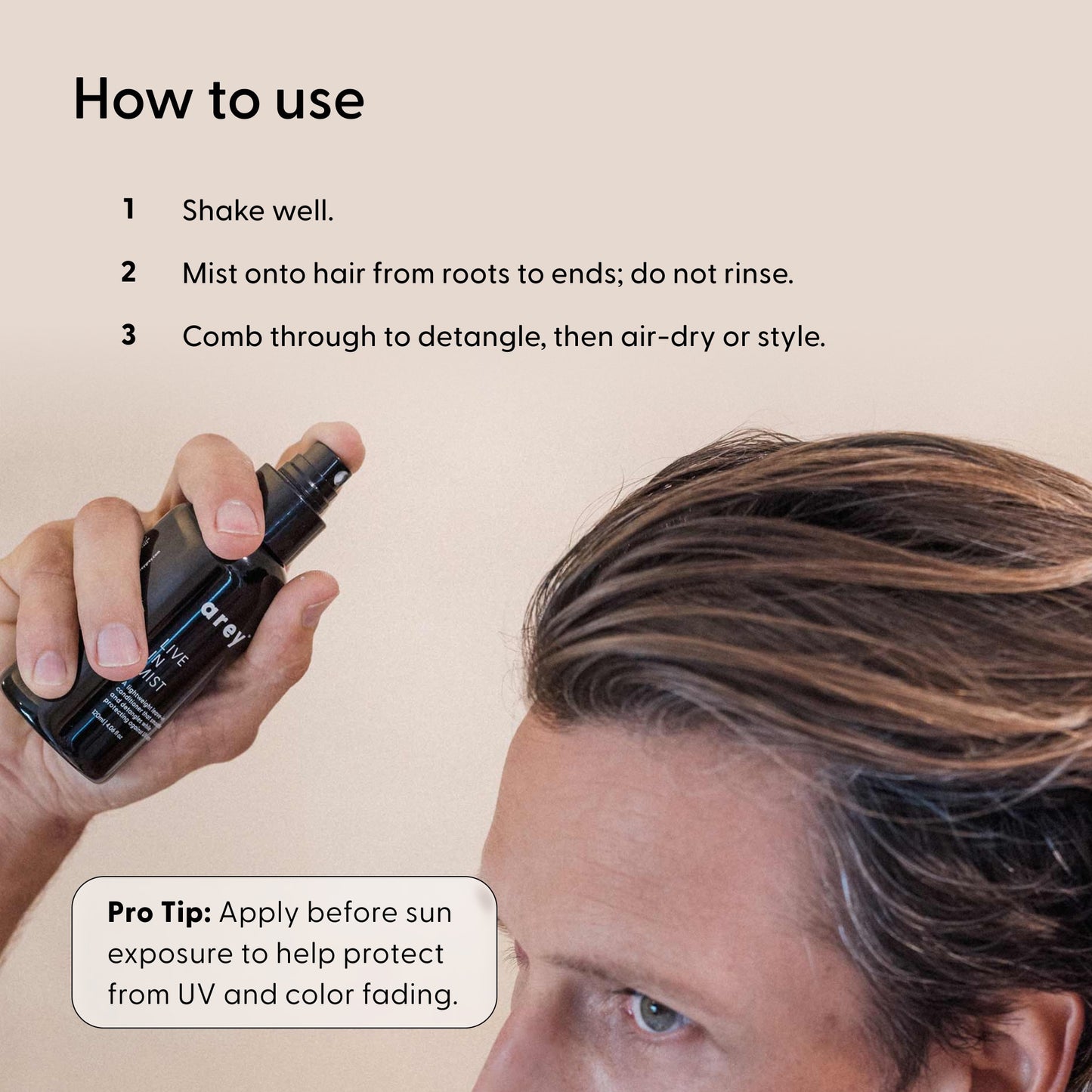 A person applies Arey’s Live In Mist Leave-In Conditioner by shaking the bottle and misting it onto their hair from roots to ends—no rinsing required. The text explains: comb through to detangle, then air-dry or style as desired. Infused with nourishing Raspberry Seed Oil, this conditioner offers additional benefits. Pro tip: apply before sun exposure for UV protection and color preservation.