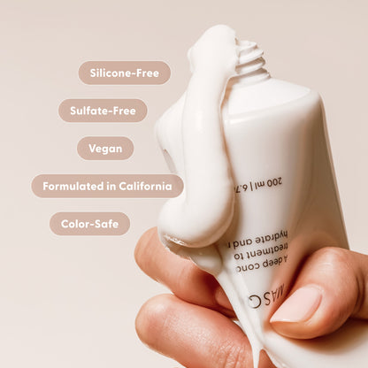 A hand holds a tube of Arey’s Masque Deep Conditioner with product oozing out, highlighting this hydrating hair treatment. Text bubbles list features: Silicone-Free, Sulfate-Free, Vegan, Formulated in California, Color-Safe. The background is a neutral beige—perfect for showcasing this silicone-free conditioner designed for effective damaged hair repair.