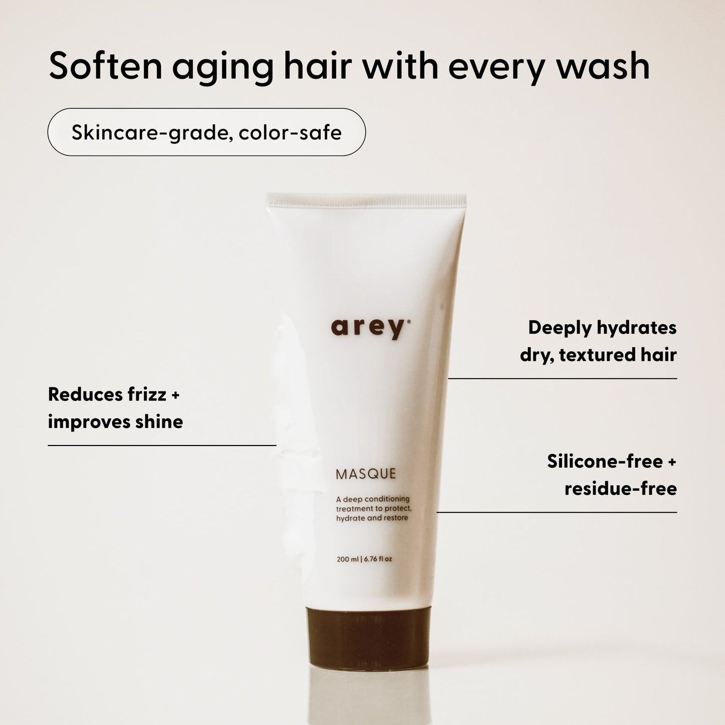 A white tube labeled Arey Masque Deep Conditioner stands upright, with surrounding text highlighting its hair benefits: repairs damaged hair, improves shine, deeply hydrates with a silicone-free formula, leaves no residue, features skincare-grade ingredients, and is color-safe.