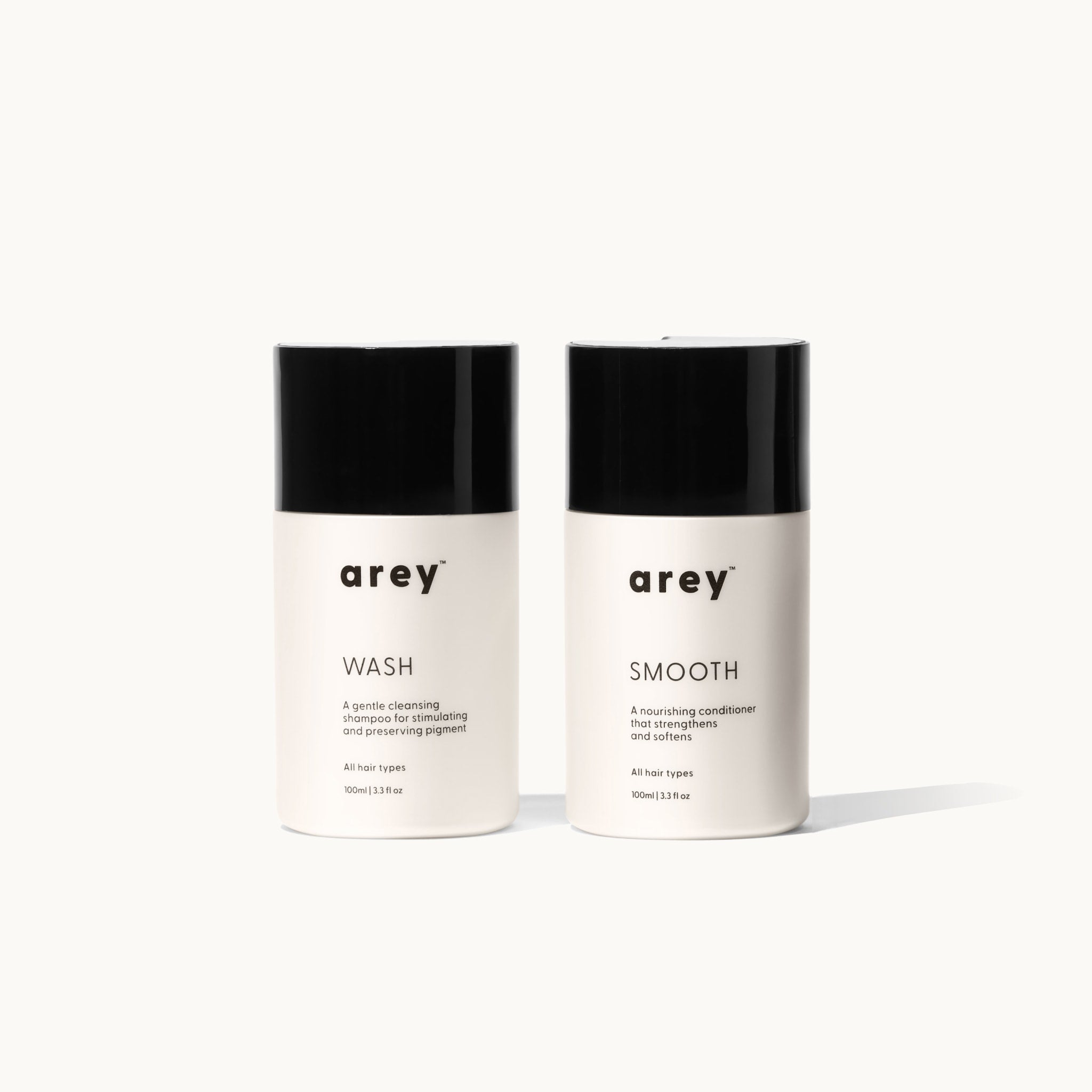 Two Arey Mini Duo travel-size bottles side by side on a white background. Left: arey® Wash — 
