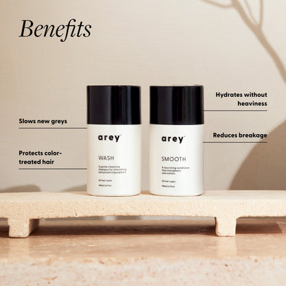 Two bottles of 'arey' hair care products on a platform with text highlighting benefits.