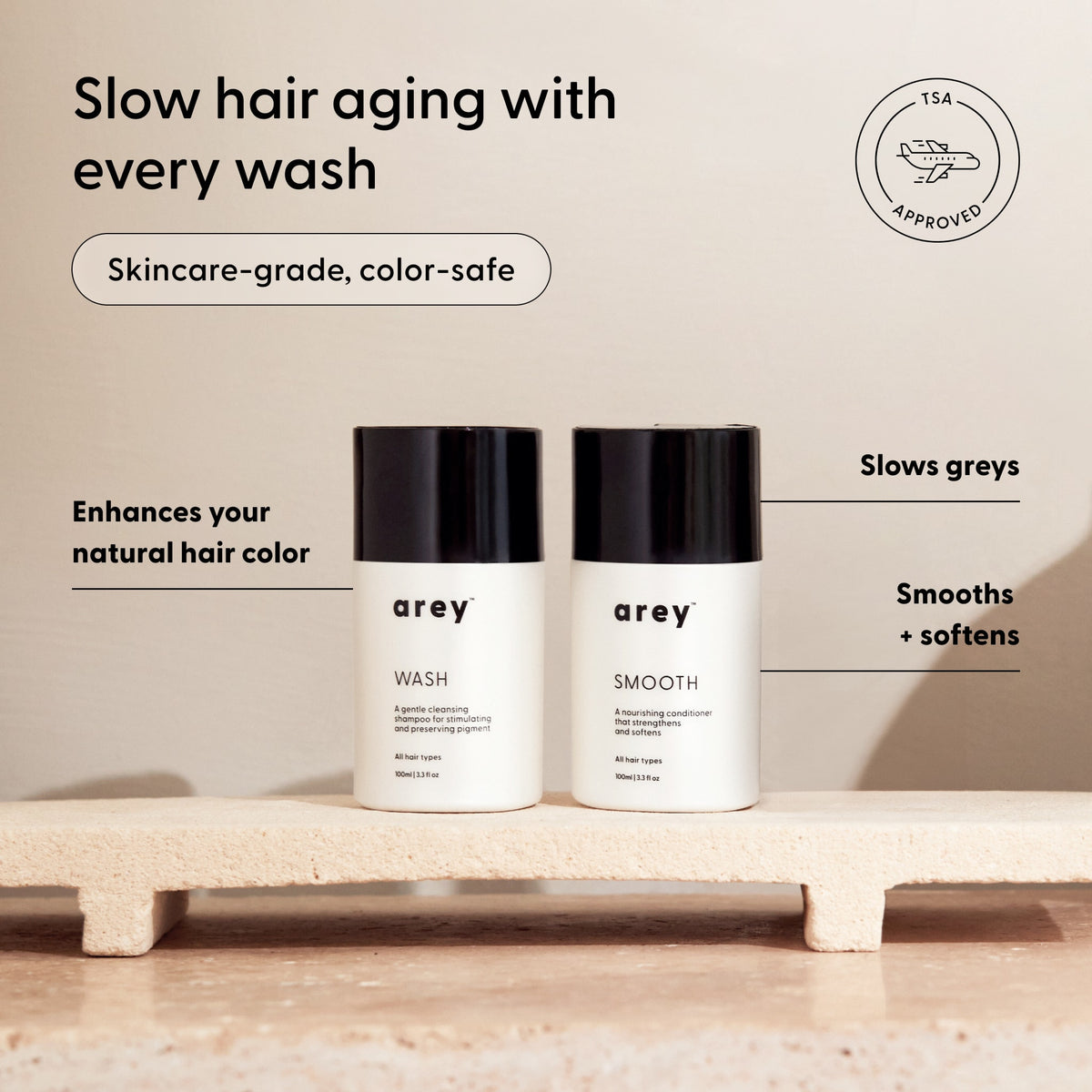 Two Arey Mini Duo bottles labeled Wash and Smooth sit on a textured shelf, highlighted by text showcasing their science-forward, anti-aging, color-safe, and TSA-approved features for maintaining your hair’s natural color and softness. Experience healthier hair with Arey’s innovative in-shower care—designed to support your hair at every step.