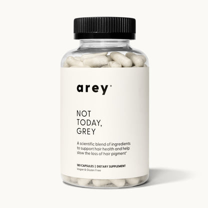 Product shot of the Arey Not Today Grey 3-month supply bottle on a white/cream background. Label reads: arey® Not Today, Grey. "A scientific blend of ingredients to support hair health and help slow the loss of hair pigment.†" 180 Capsules, Dietary Supplement, Vegan & Gluten Free.