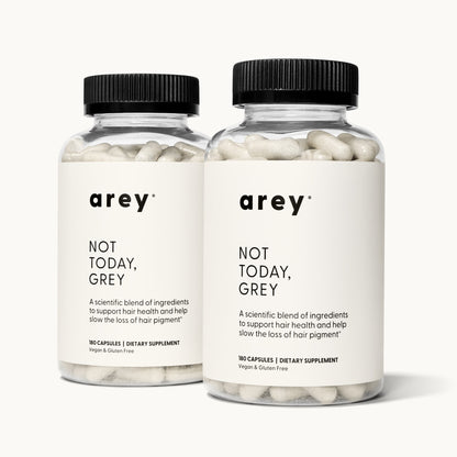 Two bottles of Arey Not Today Grey supplement on a white background, representing the 6-month supply. Both bottles show label text: arey® Not Today, Grey. "A scientific blend of ingredients to support hair health and help slow the loss of hair pigment." 180 Capsules, Dietary Supplement, Vegan & Gluten Free.