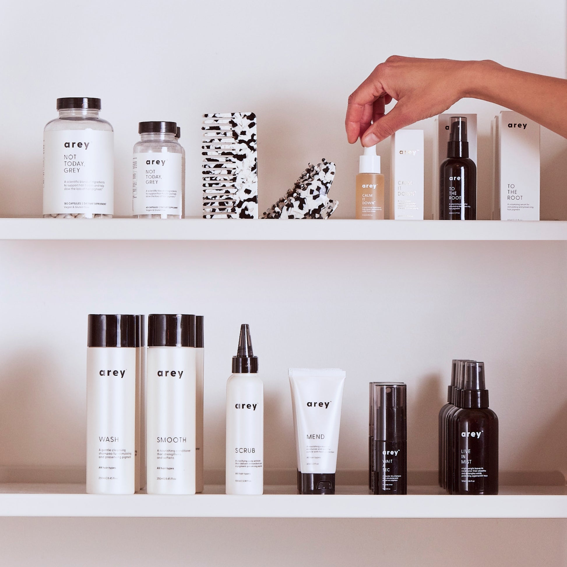 Image of someone taking Calm It Down off of a shelf with other Arey products