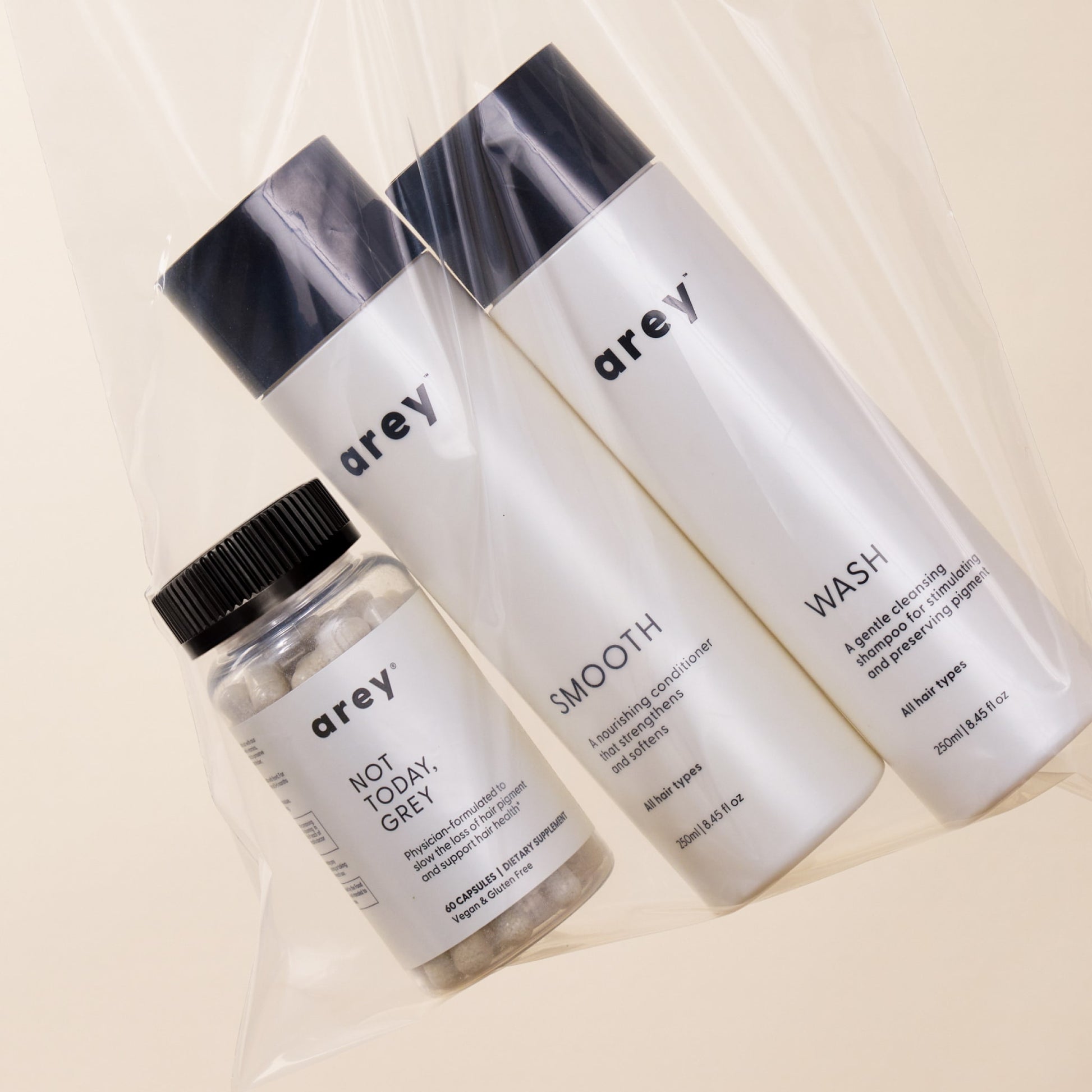 Three Arey hair care products from The Inside-Out Set are displayed in a clear plastic bag against a light beige background.
