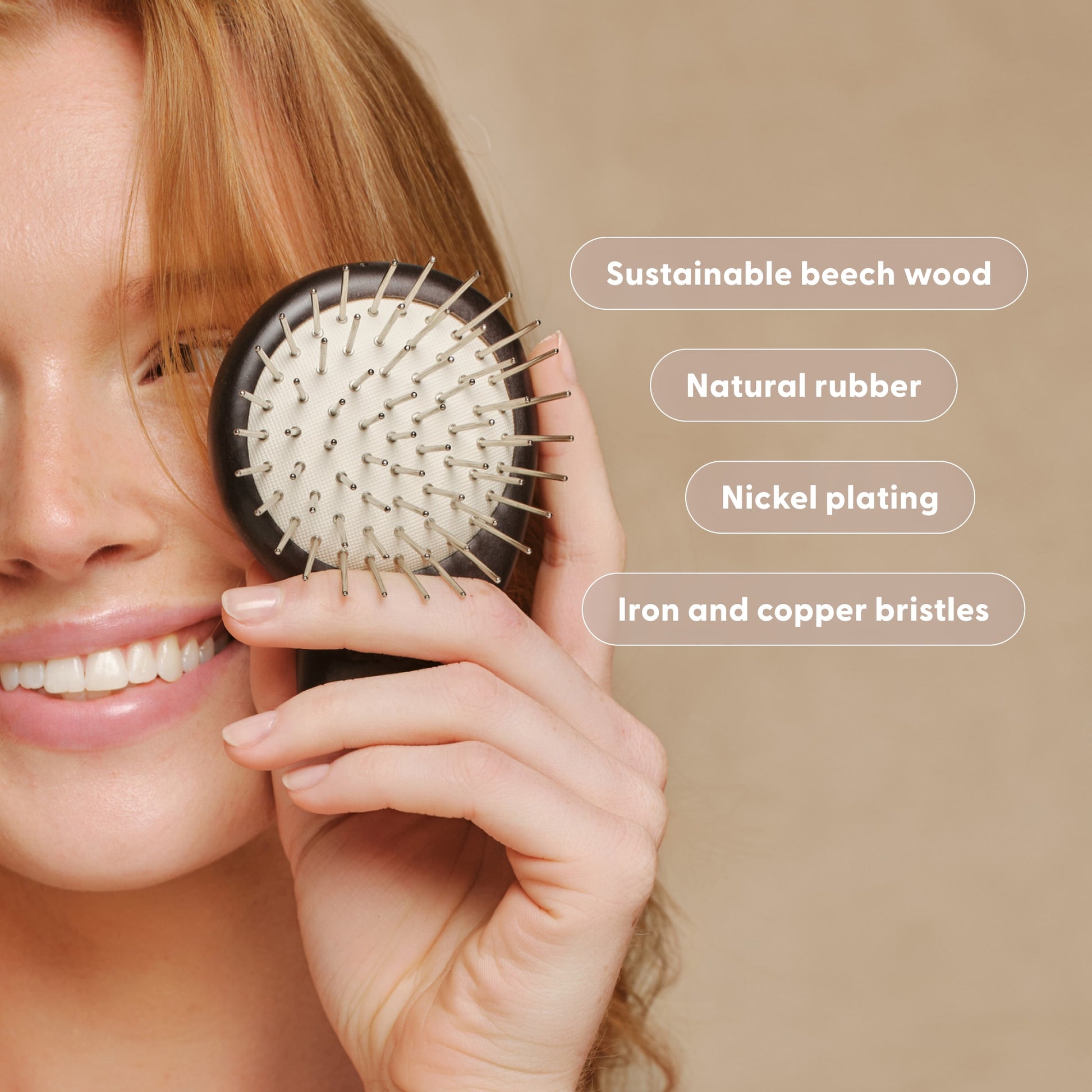 Woman smiling and holding the Arey Scalp Brush with materials labeled. Labels: Sustainable beech wood. Natural rubber. Nickel plating. Iron and copper bristles.