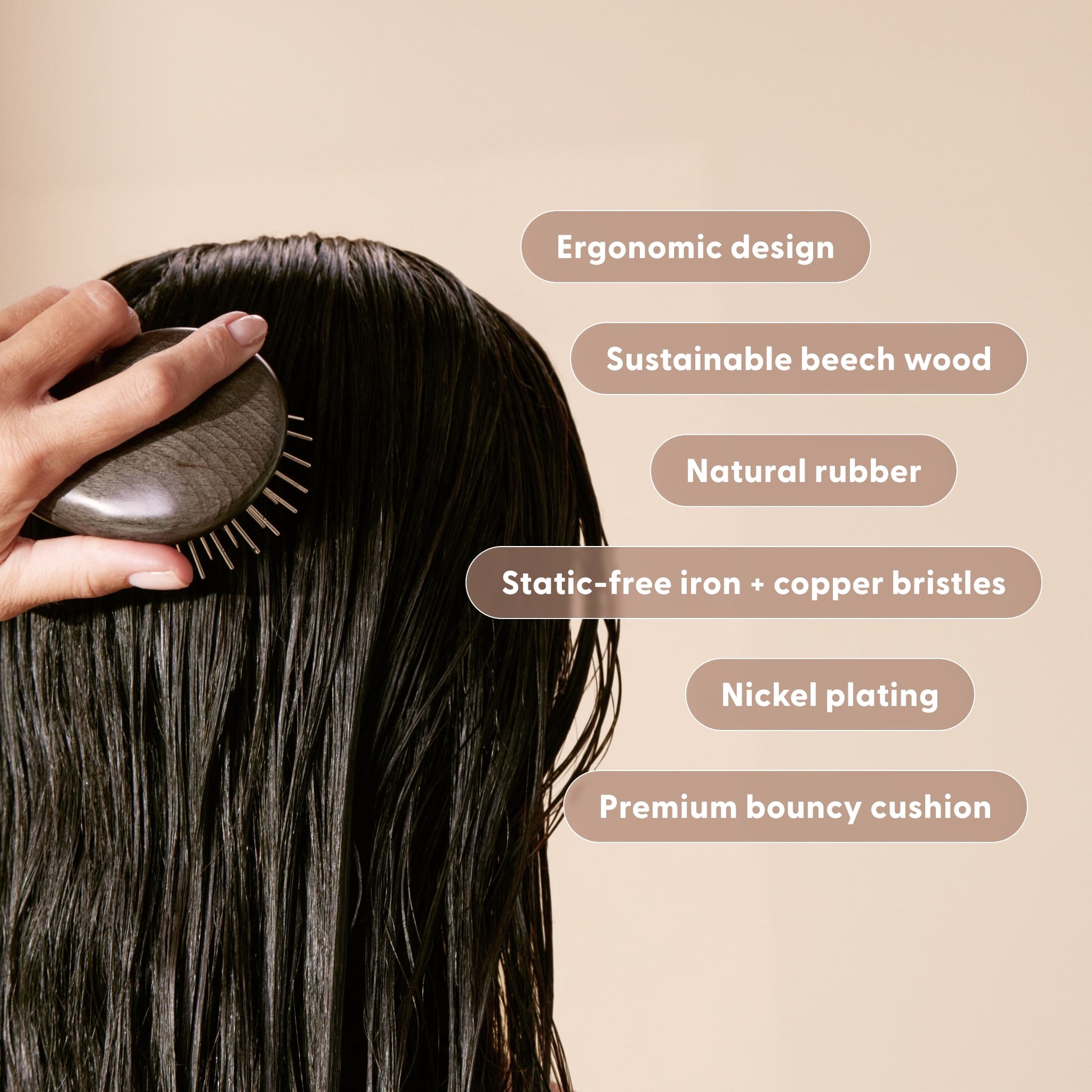 Woman holding the Arey Scalp Brush with value props labeled. Labels: Ergonomic design. Sustainable beech wood. Natural rubber. Nickel plating. Static-free Iron and copper bristles. Premium bouncy cushion