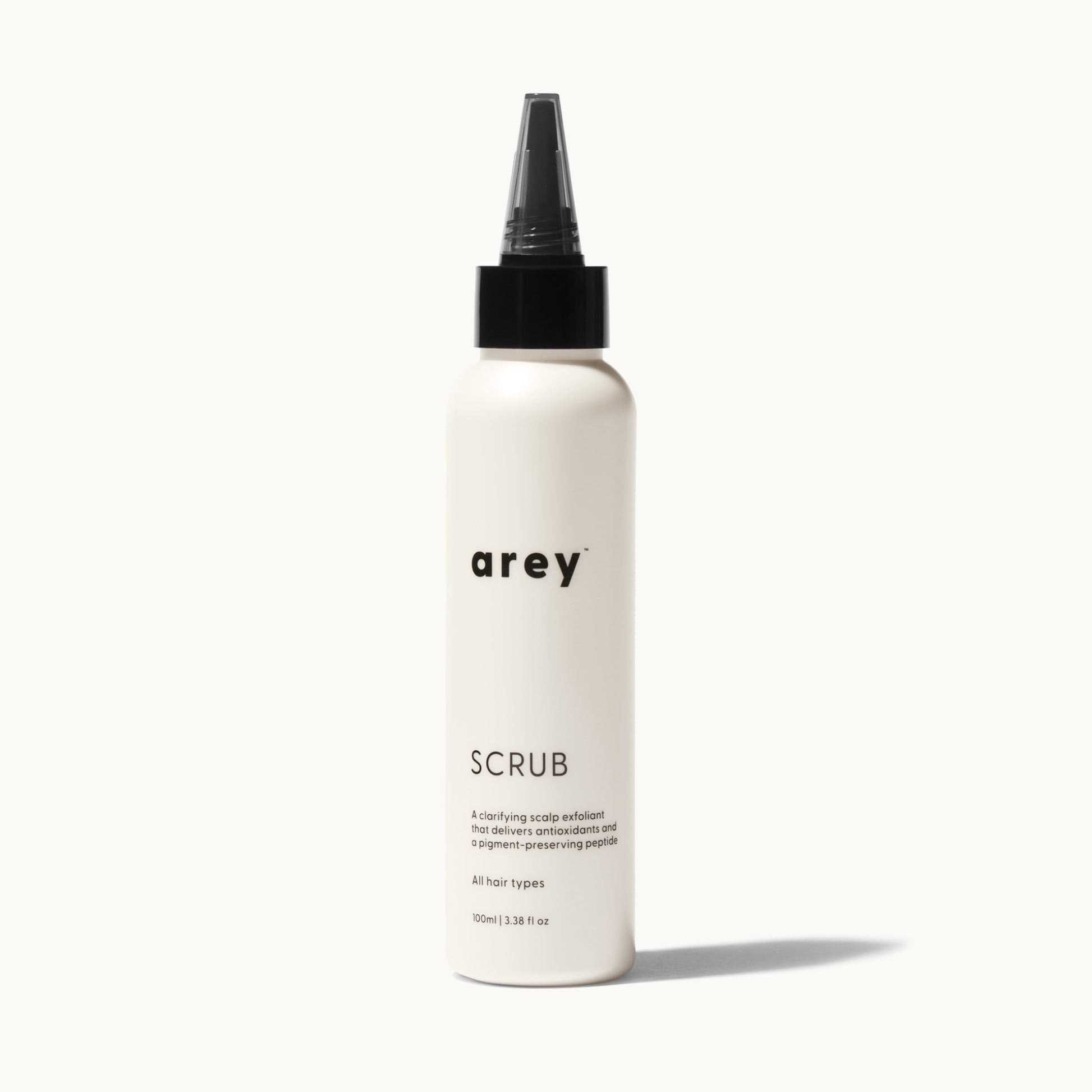 Arey Scalp Scrub bottle on cream background. Label reads: arey. SCRUB. A clarifying scalp exfoliant that delivers antioxidants and a pigment-preserving peptide. All hair types. 100ml / 3.38 fl oz.