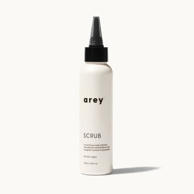 Arey Scalp Scrub bottle on cream background. Label reads: arey. SCRUB. A clarifying scalp exfoliant that delivers antioxidants and a pigment-preserving peptide. All hair types. 100ml / 3.38 fl oz.