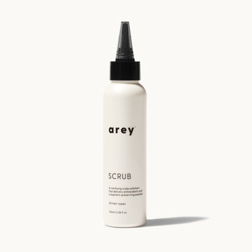 Arey Scalp Scrub bottle on cream background. Label reads: arey. SCRUB. A clarifying scalp exfoliant that delivers antioxidants and a pigment-preserving peptide. All hair types. 100ml / 3.38 fl oz.
