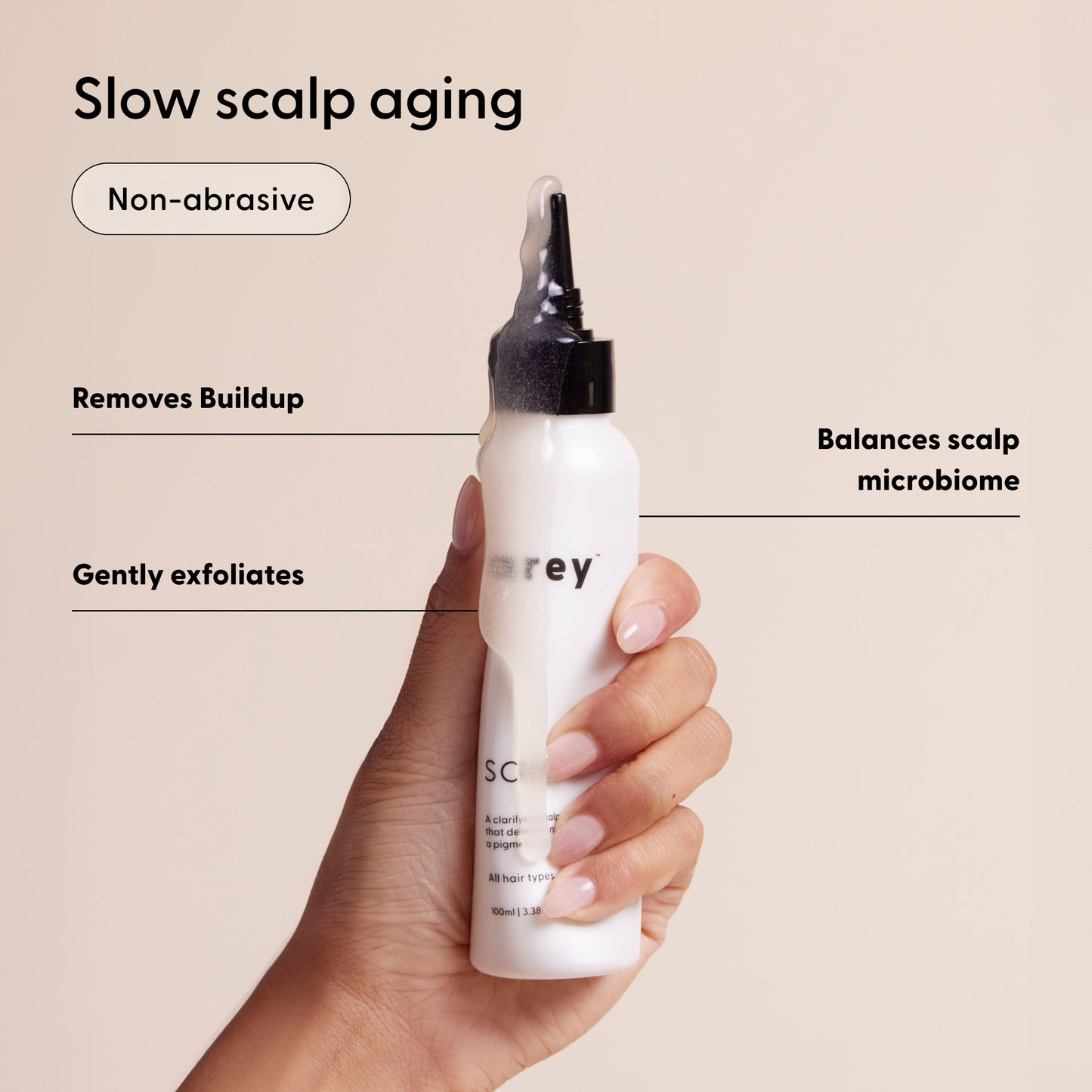 A hand holds a white bottle of Arey Scrub Scalp Exfoliant with a nozzle tip. Text highlights: Slow scalp aging, Non-abrasive, Removes buildup, Balances scalp microbiome, and gently exfoliates with salicylic acid.