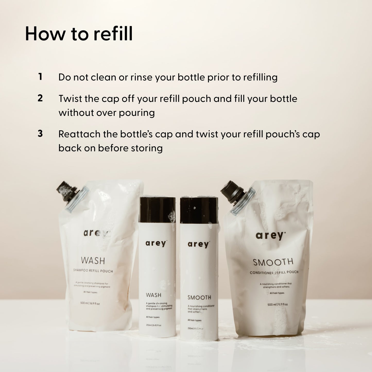 Four bottles and pouches of Arey’s The Shower Duo Refill are displayed on a surface. Above them, the text explains how to refill your Wash Shampoo and Smooth Conditioner bottles using the refill pouches—reminding you not to rinse first, pour carefully, and recap—for effortless in-shower care with Arey.