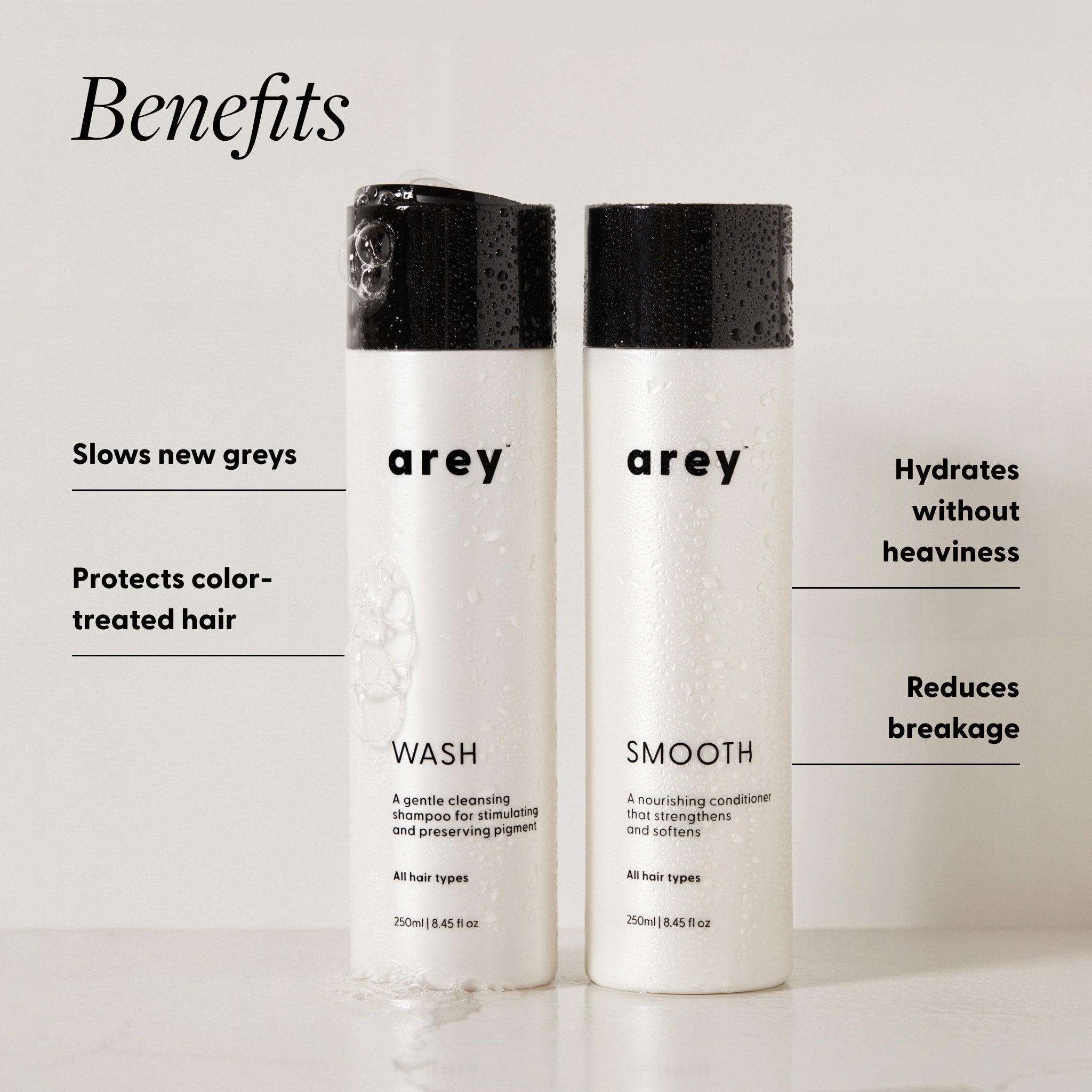Arey Shower Duo Wash and Smooth bottles (250ml each) with benefits labeled. Text reads: Benefits — Slows new greys. Protects color-treated hair. Hydrates without heaviness. Reduces breakage.