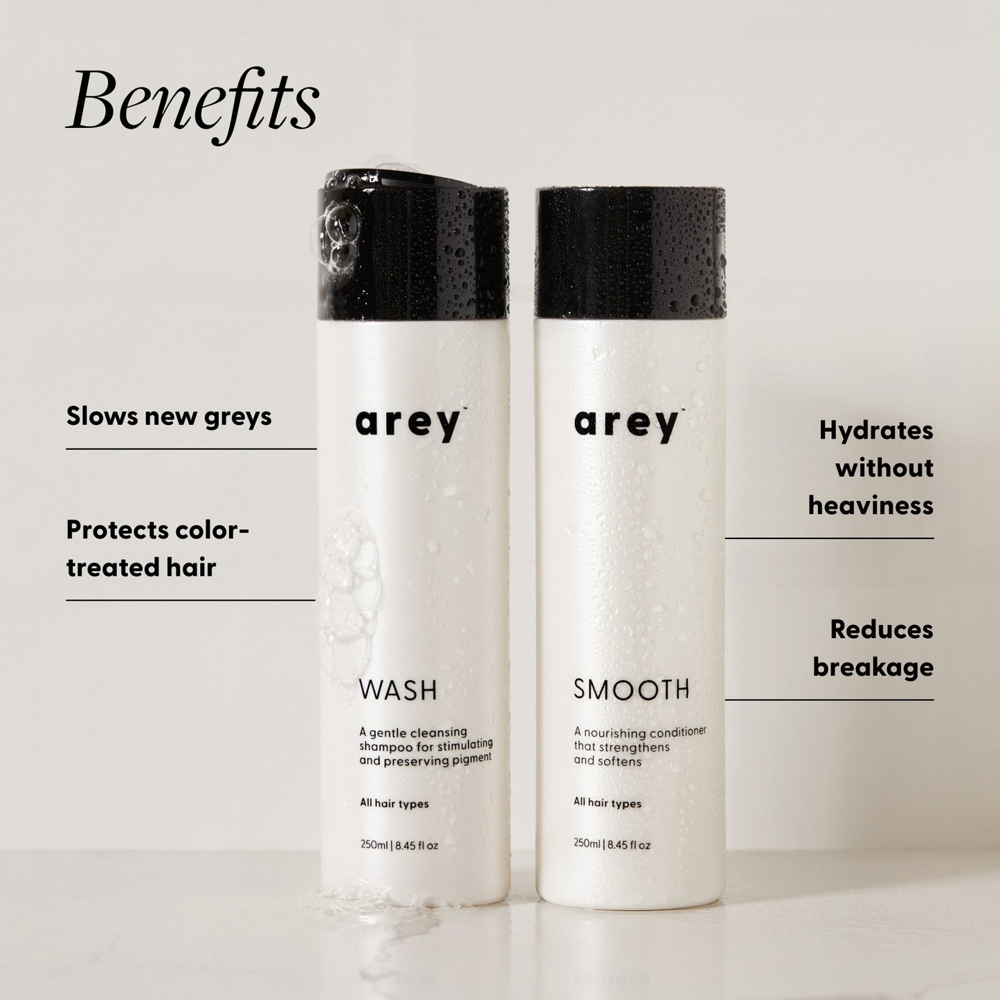 Arey Shower Duo Wash and Smooth bottles (250ml each) with benefits labeled. Text reads: Benefits — Slows new greys. Protects color-treated hair. Hydrates without heaviness. Reduces breakage.