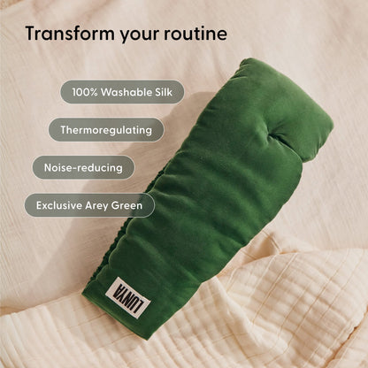 A green silk eye mask from Arey’s The Sleep Ritual Set rests on a beige quilt, with text spotlighting its features: washable silk, thermoregulating properties, noise reduction, and an exclusive Arey Green color—making it the ideal companion to your overnight scalp serum routine for an elevated hair wellness experience.