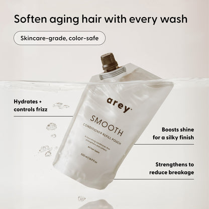 An Arey Smooth Conditioner Refill pouch submerged in water, showcasing key benefits: hydrates, controls frizz, boosts shine, reduces breakage, is color-safe, and suitable for aging hair—this nourishing conditioner from Arey provides advanced hair repair with a clean formula for healthier-looking hair.