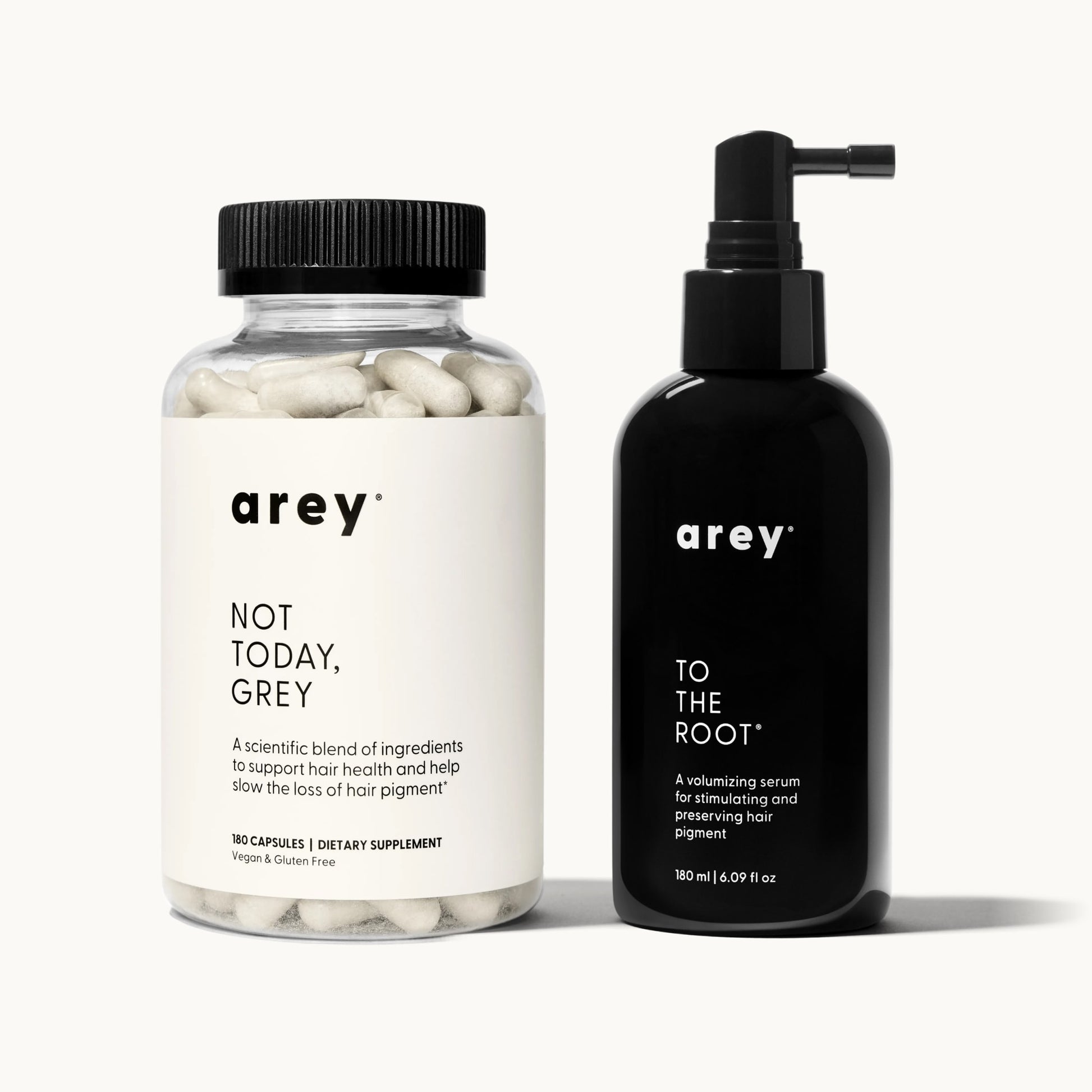 Arey 3-month system supply on a cream background. Left: Arey Not Today, Grey supplement bottle (180 capsules, Dietary Supplement, Vegan & Gluten Free). Right: Arey To The Root serum bottle (180 ml / 6.09 fl oz), a volumizing serum for stimulating and preserving hair pigment.