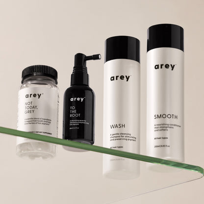 Editorial image of Not Today, Grey (supplements), To The Root (serum), Wash shampoo, and Smooth conditioner on a glass shelf.