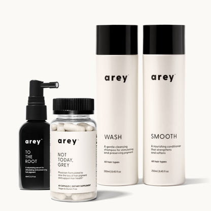 Lineup product photo of the Arey Essentials Kit on a cream background. Left to right: To The Root scalp serum (black spray bottle, 66ml), Not Today, Grey supplement (clear jar, 60 capsules, Vegan and Gluten Free), Wash shampoo (white bottle, 250ml), and Smooth conditioner (white bottle, 250ml).