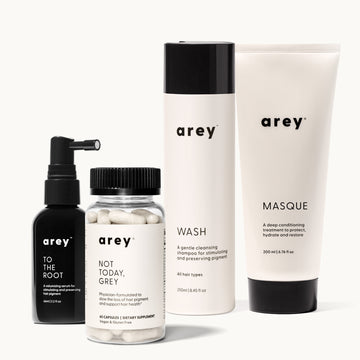 Four Arey Restorative Kit products on a white background: To The Root serum ("A volumizing serum for stimulating and preserving hair pigment", 66ml/2.2 fl oz), Not Today Grey capsules ("Physician-formulated to slow the loss of hair pigment and support hair health", 60 Capsules, Dietary Supplement, Vegan & Gluten Free), Wash shampoo ("A gentle cleansing shampoo for stimulating and preserving pigment", All hair types, 250ml/8.45 fl oz), and Masque ("A deep conditioning treatment to protect, hydrate and restor