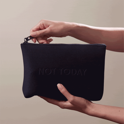Animated GIF of hands holding the Arey "Not Today" black travel bag. The zippered pouch has "NOT TODAY" embossed on the front.