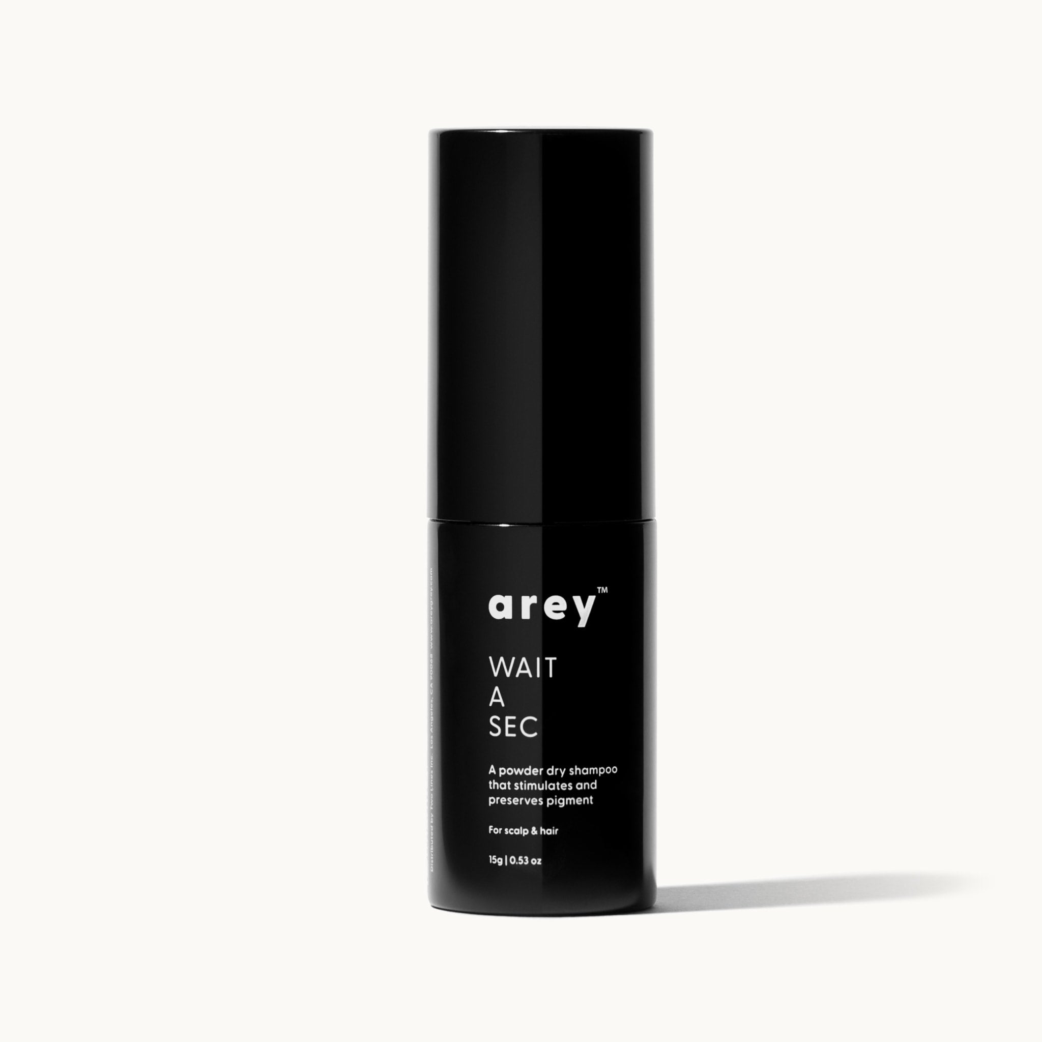 Arey Wait A Sec bottle on a cream background. Label reads: arey. WAIT A SEC. A powder dry shampoo that stimulates and preserves pigment. For scalp & hair. 15g / 0.53 oz.