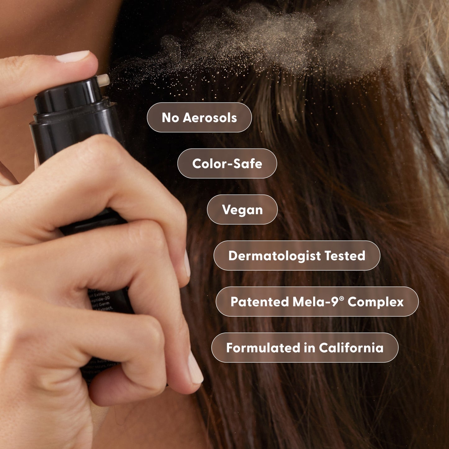 A person sprays Arey Wait A Sec® Dry Shampoo—a non-aerosol formula—onto brown hair. Text bubbles read: Absorb Oil, Boost Volume, No Aerosols, Color-Safe, Vegan, Dermatologist Tested, Patented Mela-9® Complex, Formulated in California.