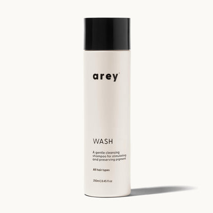Arey Wash bottle on a cream background. Label reads: arey. WASH. A gentle cleansing shampoo for stimulating and preserving pigment. All hair types. 250ml / 8.45 fl oz.
