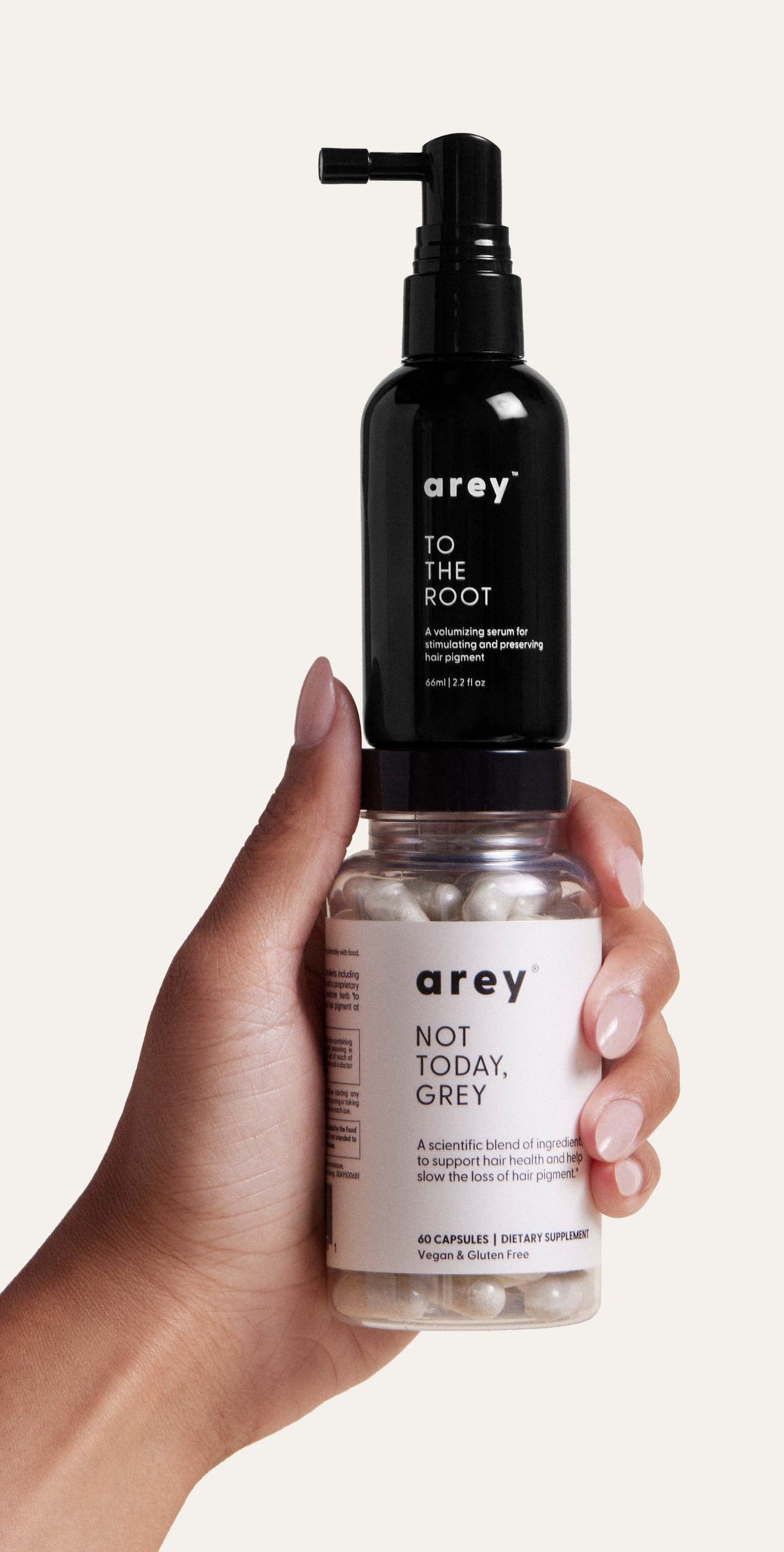 A hand holding Arey To The Root serum and Not Today, Grey supplement.