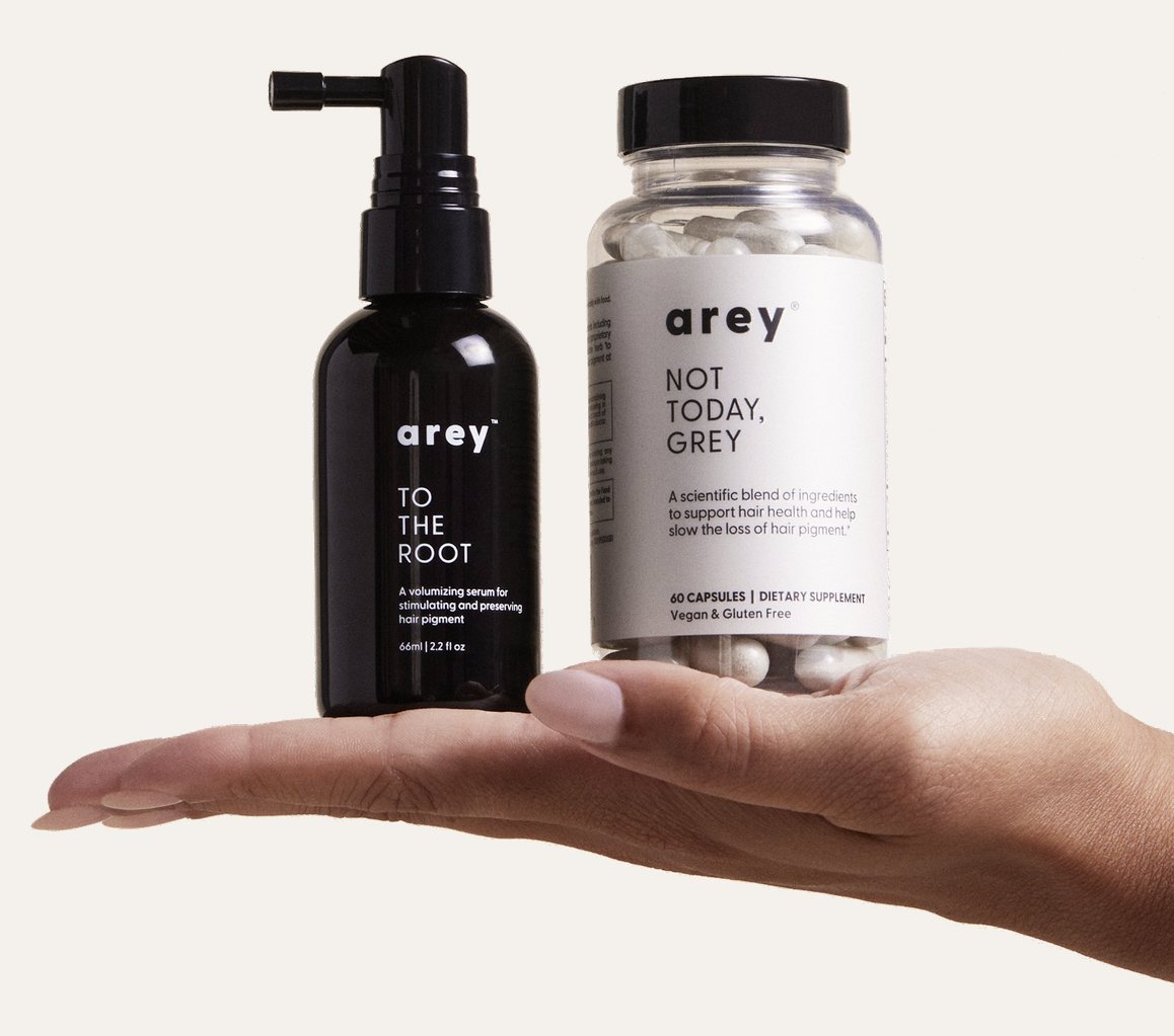 A hand holding Arey To The Root serum and Not Today, Grey supplement.